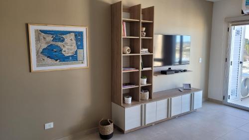 sala de estar con estante de libros y TV en Cuatro Vientos en Puerto Madryn
