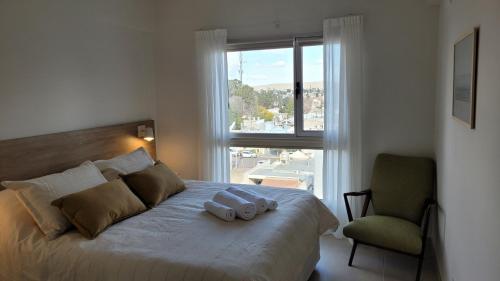 a bedroom with a bed with a chair and a window at Departamento moderno con cochera y parrilla, amplio y luminoso in Puerto Madryn