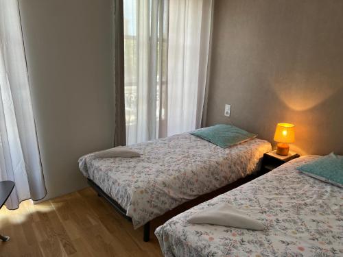 2 Betten in einem kleinen Zimmer mit Fenster in der Unterkunft Le Lys in Lassay