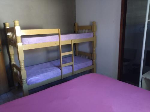 a bunk bed with purple bunk beds in a room at Casinha Sossego na Praia in Caraguatatuba