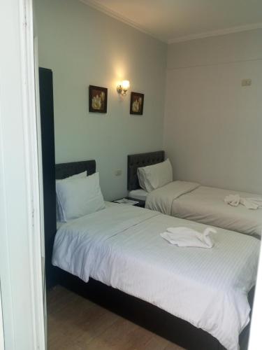 two beds in a room with white sheets at New Panorama Palace in Cairo