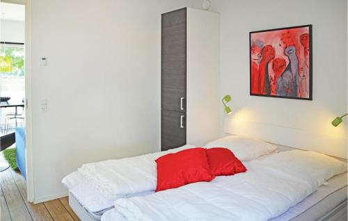 a white bed with a red pillow on top of it at Beautiful Home In Ringkbing With 2 Bedrooms And Wifi in Hee