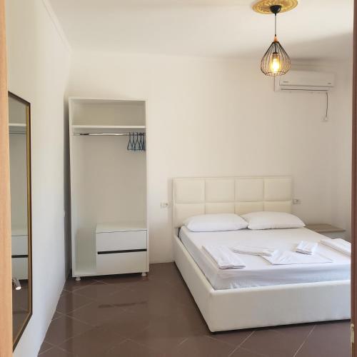 a white bedroom with a bed and a mirror at Pomegranates & Olives Guesthouse in Durrës