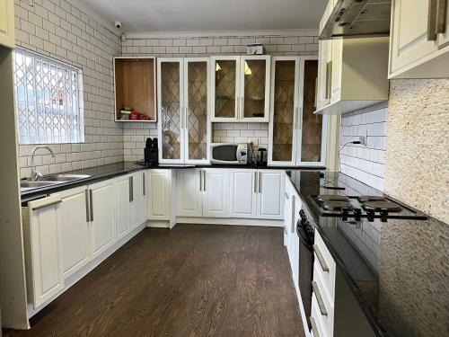 a white kitchen with white cabinets and a sink at Joyous Lodges in Cape Town