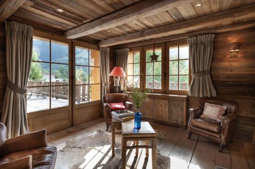 a living room with chairs and a table and windows at Chalet Ruitor, chalet 500 m2 luxueux de caractère in Sainte-Foy-Tarentaise