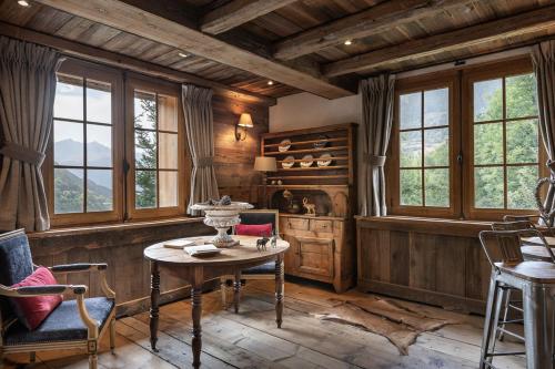 a room with a table and chairs and windows at Chalet Ruitor, chalet 500 m2 luxueux de caractère in Sainte-Foy-Tarentaise
