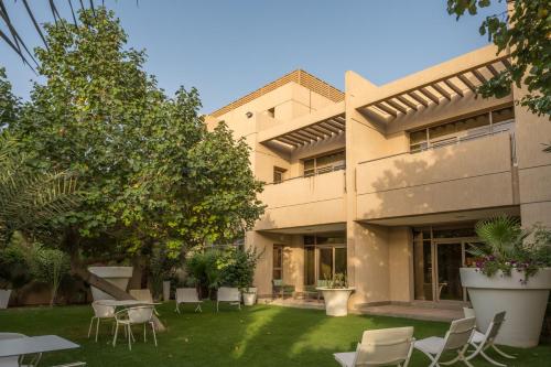 an apartment building with chairs and a yard at Vivienda Hotel Villas Granada in Riyadh