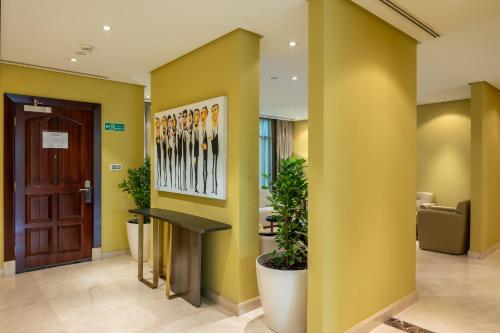 vestíbulo con paredes amarillas, mesa y sillas en Vivienda Hotel Villas Granada en Riad