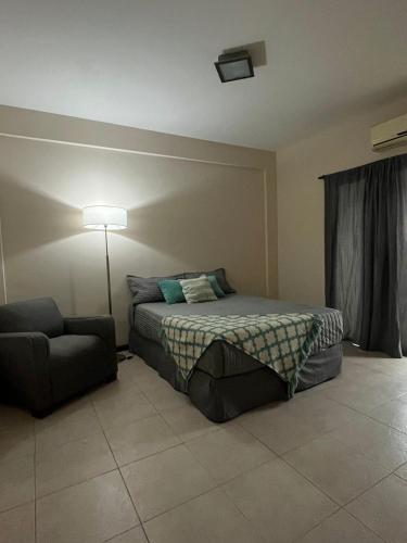 a bedroom with a bed and a chair and a lamp at TempoExtra in Corrientes