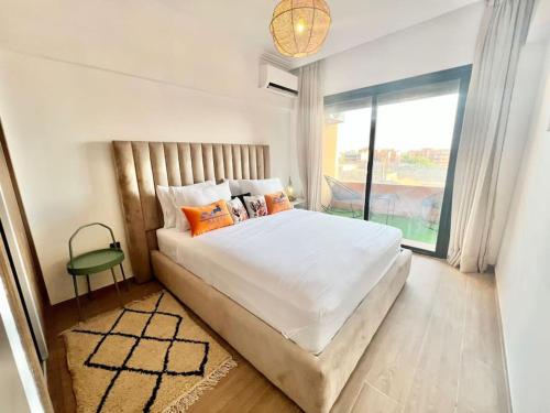 - une chambre avec un grand lit et une grande fenêtre dans l'établissement Cozy&Elegant apartment/pool/city center/Gueliz, à Marrakech