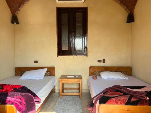a room with two beds and a table and a window at Zad El Mosafer Guest House in Tunis