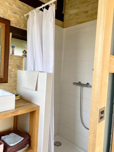 La salle de bains est pourvue d'une douche avec rideau de douche blanc. dans l'établissement Maison Chaumont, à Vézac