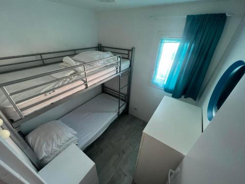 une petite chambre avec deux lits superposés et une fenêtre dans l'établissement T3 front de mer avec piscine, à Frontignan