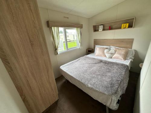 a small bedroom with a bed and a window at Caravan Delta 2 Bedroom in Rhyl in Rhyl