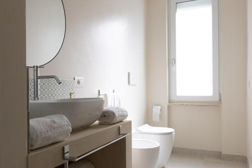 La salle de bains est pourvue d'un lavabo, de toilettes et d'un miroir. dans l'établissement Oronti Accommodations, à Lecce