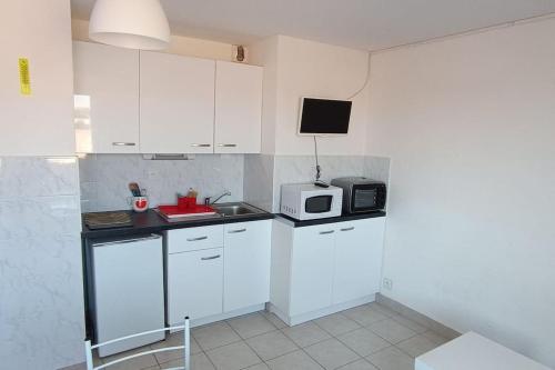 une petite cuisine avec des armoires blanches et un micro-ondes dans l'établissement Studio maison de la mer, à Saint Pierre La Mer