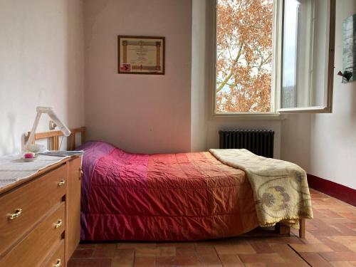 um quarto com uma cama com um cobertor vermelho e uma janela em Palazzo Giulia em Brisighella