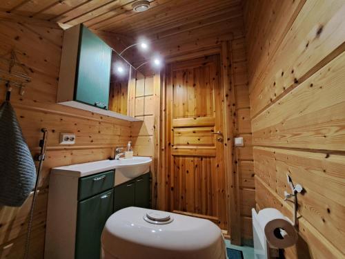 La salle de bains en bois est pourvue de toilettes et d'un lavabo. dans l'établissement Kurkimökki, à Parikkala