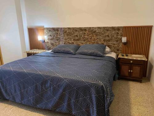 una camera da letto con un letto con un piumone blu e due tavoli di Departamento en kennedy amplio para familia a Guayaquil