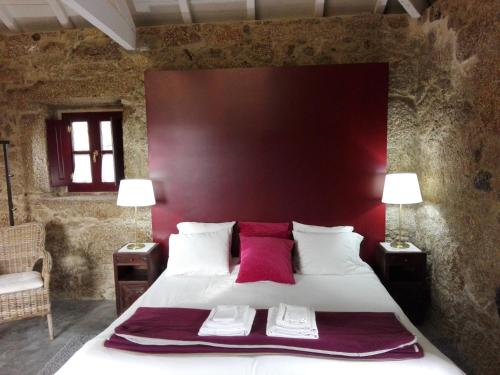 1 dormitorio con 1 cama grande y cabecero rojo en Casas da Quinta da Cancela, en Balugães