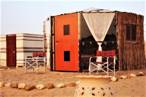 a couple of chairs and a house on the beach at Queen Desert camp in Fulayj al Mashāʼikh