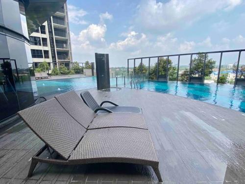a bench sitting on a deck next to a swimming pool at Stylish Nordic Suite, Pool View, 500mbps, GEO Bukit Rimau, Kota Kemuning in Shah Alam