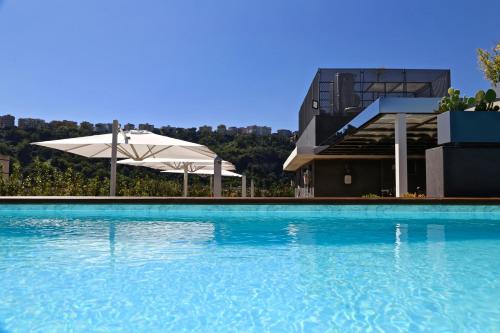 a swimming pool with an umbrella and a building at LHP Napoli Palace & SPA in Naples