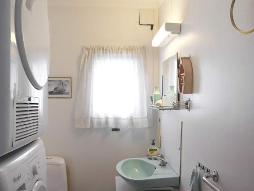 baño blanco con lavabo y ventana en Apartment Risør, en Risør
