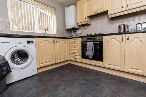 a kitchen with wooden cabinets and a washer and dryer at Stridingedge - 3 Bedroom 5 beds Sleeps 6 Ideal For Contractors in Washington