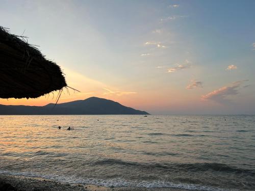 a beach with people in the water at sunset at Villa Yseni in Orikum