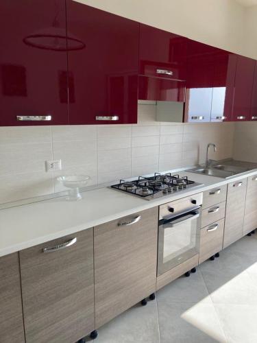 a kitchen with red cabinets and a stove top oven at IL RICCIO appartamento sul mare in Torre Melissa