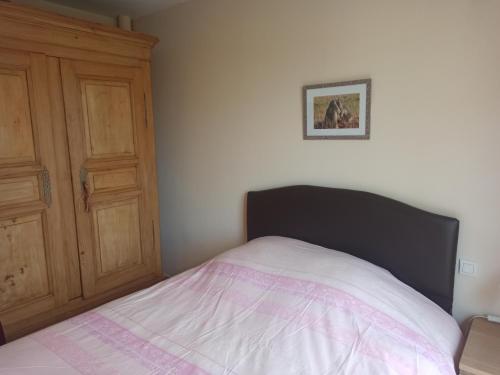 a bedroom with a bed and a wooden cabinet at Philippe et Éliane in Matha