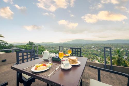 a table with food and drinks on a balcony with a view at The Hills By Blue Fox in Kandy