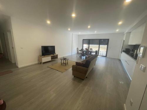 an empty living room with a couch and a television at Apartamento amplo e moderno - perto do estádio futebol in Tondela