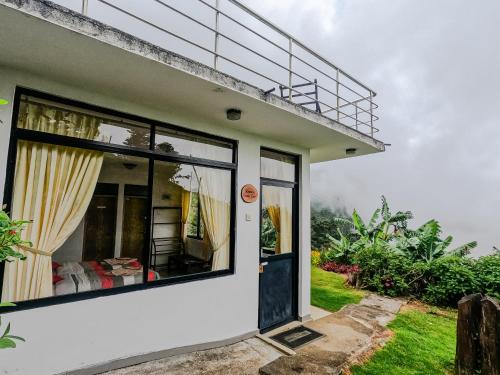 a white house with a balcony on top of it at Hill Safari - Tea Estate Villa in Ohiya