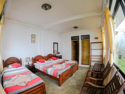 a bedroom with two beds and chairs and a window at Hill Safari - Tea Estate Villa in Ohiya