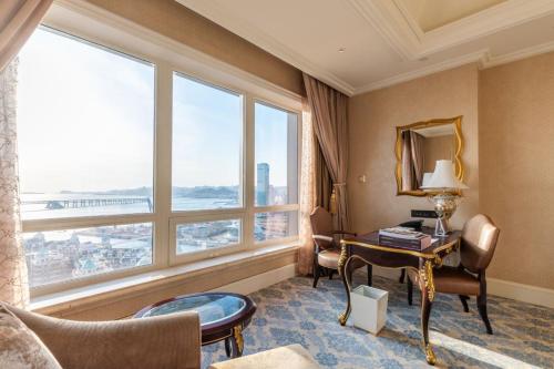 een hotelkamer met een bureau en een groot raam bij The Castle Hotel, a Luxury Collection Hotel, Dalian in Dalian