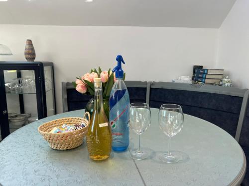 a table with two wine bottles and two wine glasses at NEON Apartman Csopak Balaton, large botanical garden, bicycles, pet&family friendly, outside kitchen, in Csopak