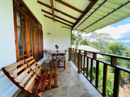 a balcony with two benches and a table on it at Racy Nature Cottage in Ella