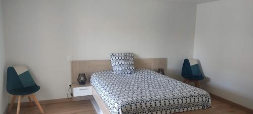 - une chambre avec un lit et deux chaises bleues dans l'établissement Maison moderne, à Jublains