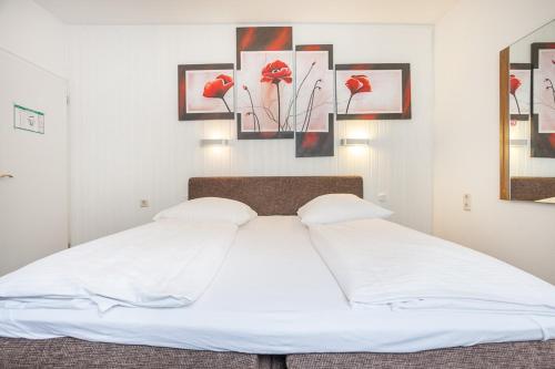 a white bed with two pillows and paintings on the wall at Hotel Union by TM in Dortmund