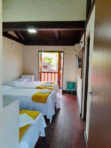 a bedroom with two beds with yellow blankets at Pousada Kyrios in Maresias