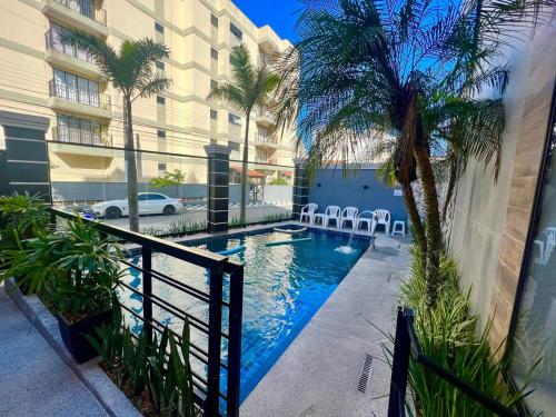 a swimming pool with chairs next to a building at Marmeu Tombo com Hidro Aquecida Privativa in Guarujá