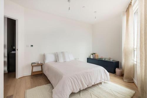 a white bedroom with a bed and a table at Cozy flat in hip East London in London