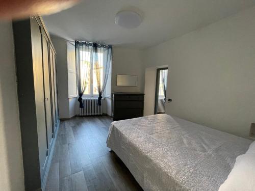 ein Schlafzimmer mit einem Bett und zwei Fenstern in der Unterkunft appartamento dell'anfiteatro in Spoleto