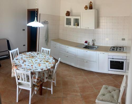 eine Küche mit einem Tisch und Stühlen sowie eine Küche mit weißen Schränken in der Unterkunft Casa Andrea in Torre Pali 