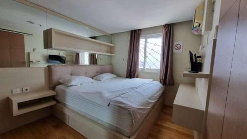 - une petite chambre avec un lit et un miroir dans l'établissement Mg Suite 1bedroom Apartment by Just Inn Management, à Semarang