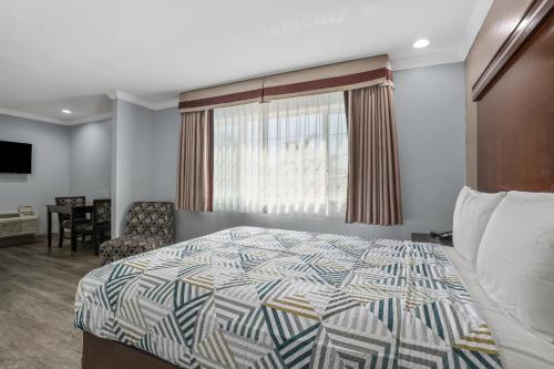 a bedroom with a bed and a chair and a window at Motel 6 Carlsbad, Ca- North in Carlsbad