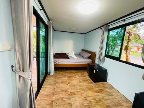 um quarto com uma cama num quarto com janelas em The Monday ที่พักราคาถูก ใกล้หาดแหลมแม่พิมพ์ em Klaeng