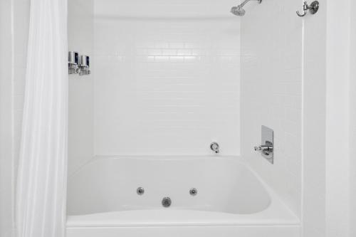a white bathroom with a tub and a sink at Four Points by Sheraton Milwaukee Airport in Milwaukee